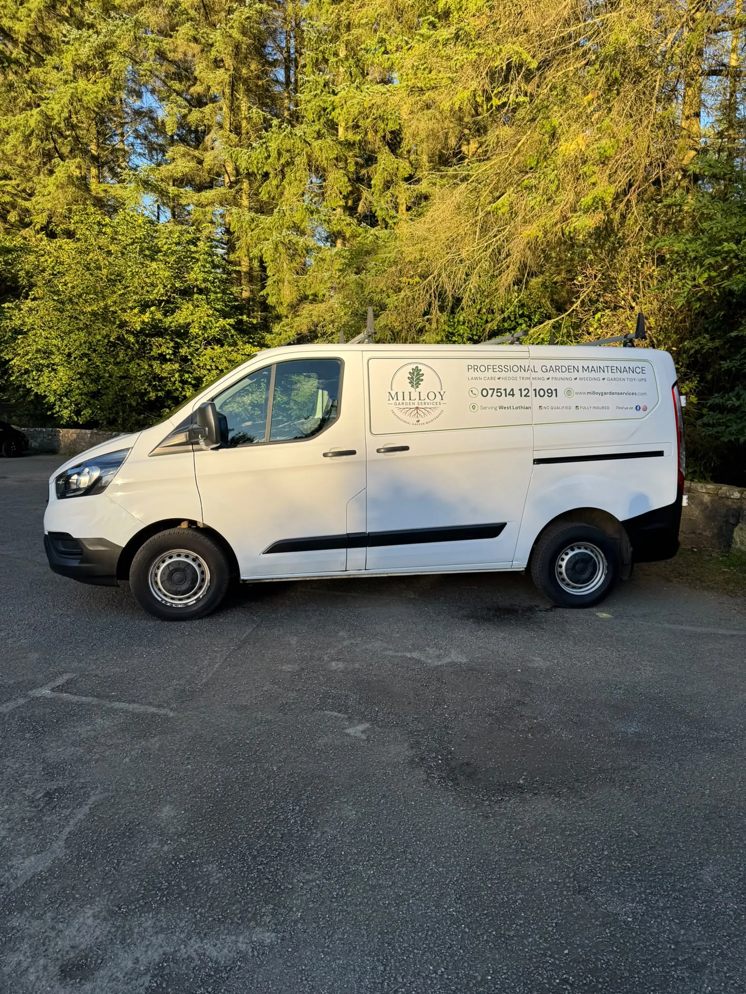 Milloy Garden Services white van with the oak-leaf logo and garden maintenance signage, parked beside trees.